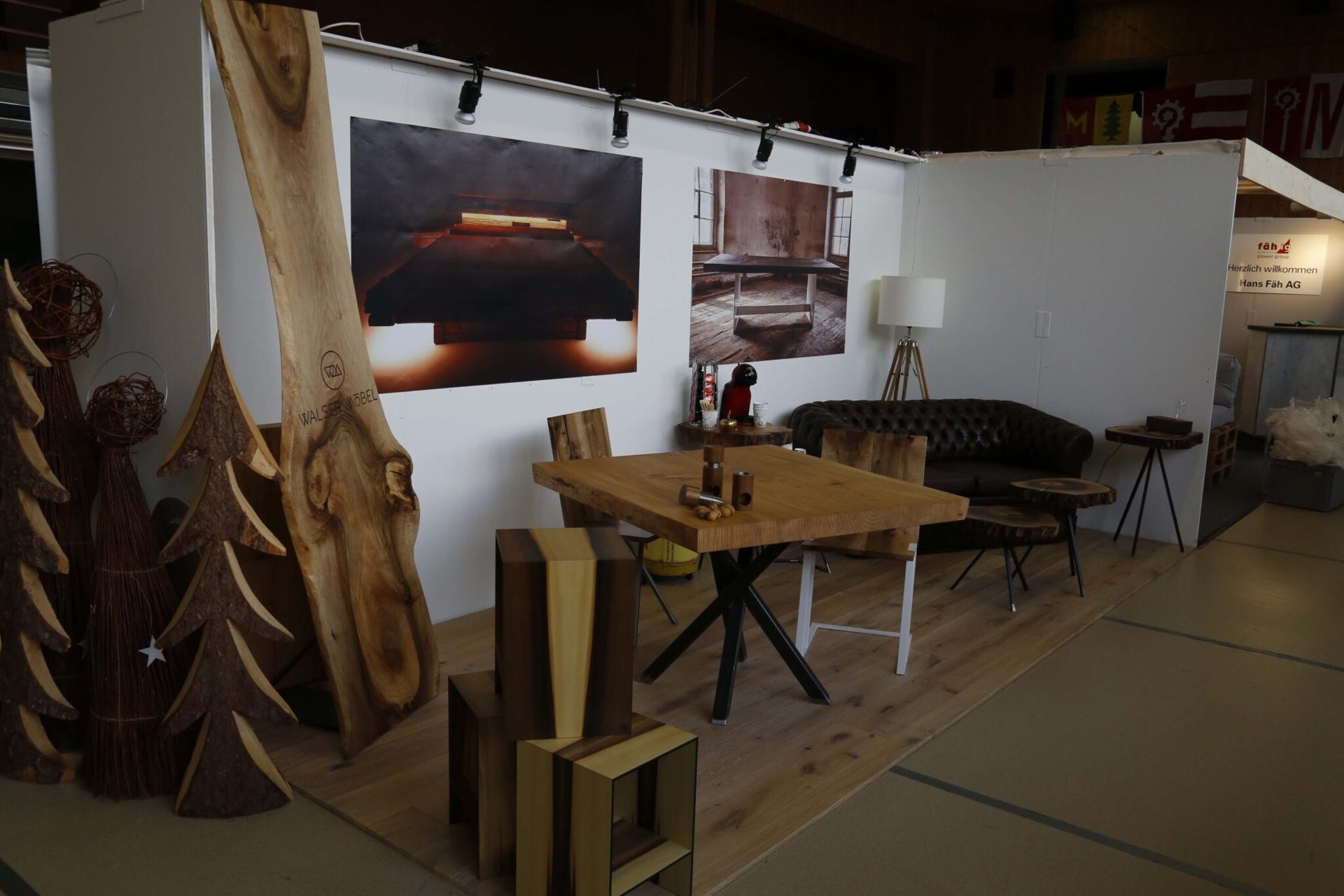 Messestand mit Massivholztisch, Hockern und geschnitzten Holzbäumen an der Quartner-Mäss